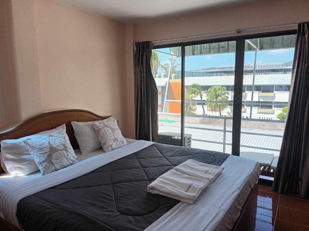 芭东海滩芭东玫瑰宾馆的一间卧室配有一张大床和毛巾