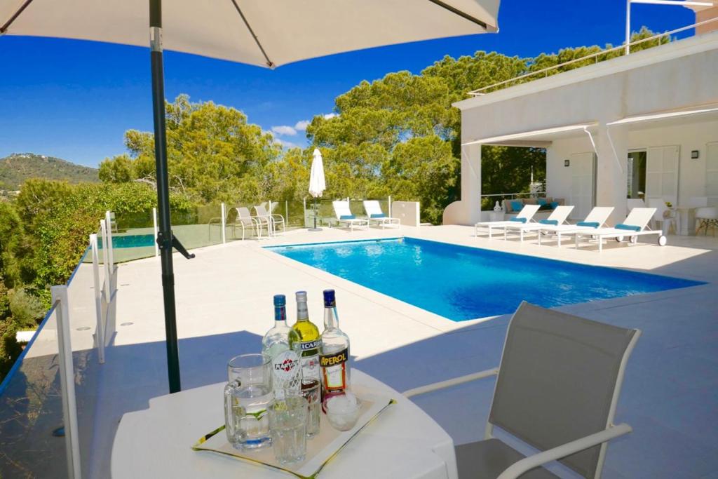 卡拉隆加Villa Dream - Santa Eulalia的游泳池旁的桌子上摆放着葡萄酒