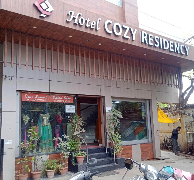 贾巴尔普尔Hotel Cozy Residency的一家酒店舒适餐厅前面的商店,外面停有摩托车