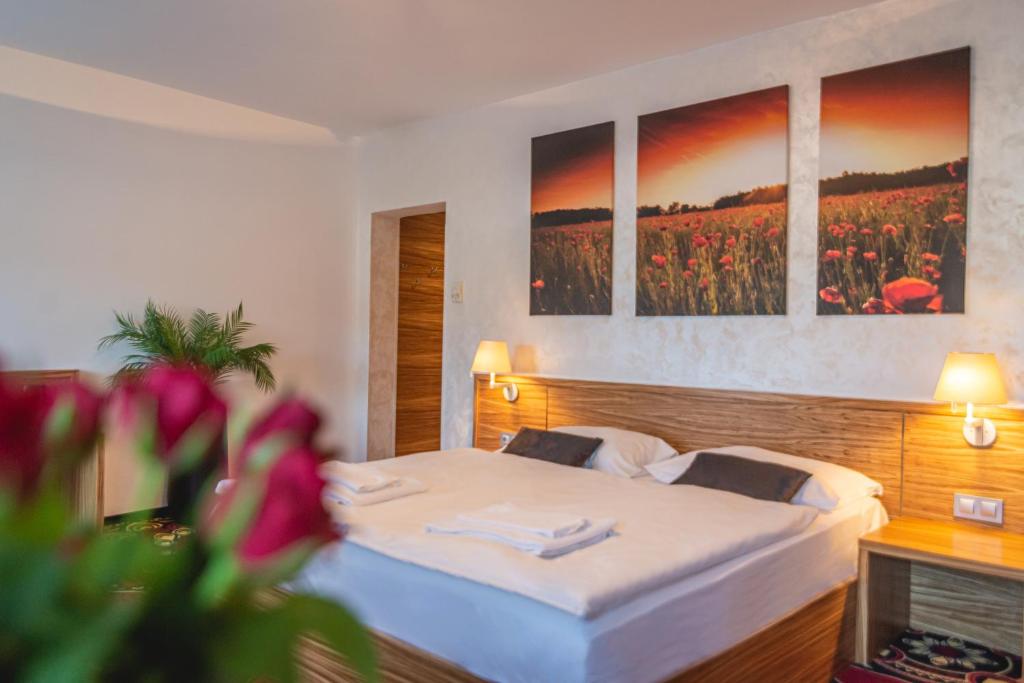 科济纳Casino & Hotel ADMIRAL Kozina的卧室配有一张墙上三幅画作的床