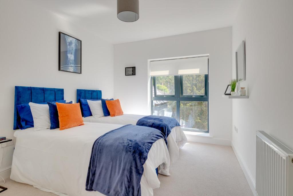 斯蒂夫尼奇Stevenage Luxury 1 Bed Apartment Sleeps 4 WIFI Free Parking Secure by JM Short Lets的白色客房的两张床,配有蓝色和橙色枕头