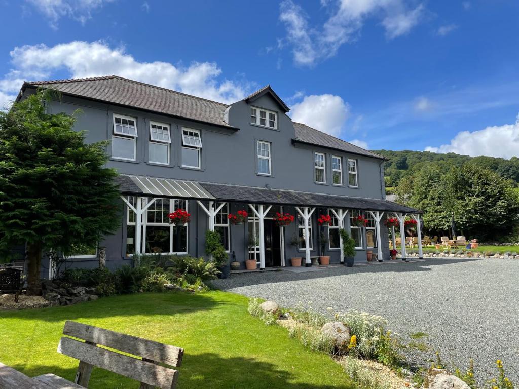 赖厄德Elan Valley Hotel的一座大灰色房子,前面有红花