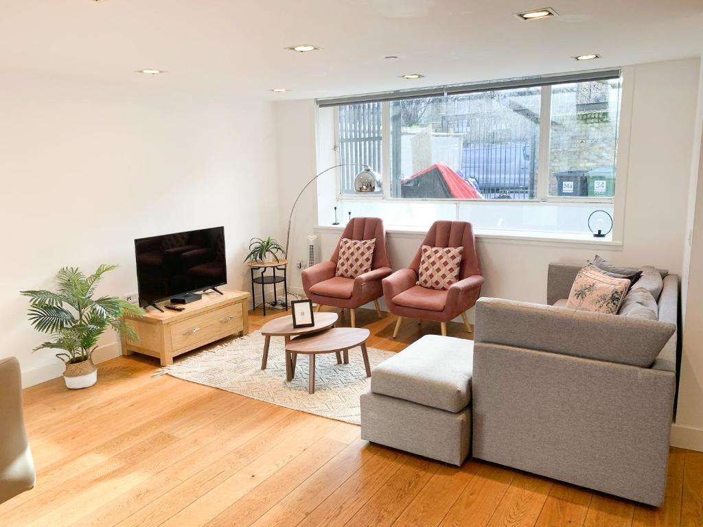 伦敦Bright, spacious, 3-bedroom Emirates apartment with terrace的客厅配有沙发、椅子和电视