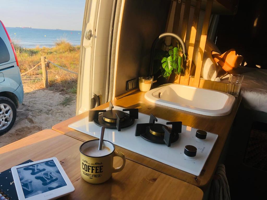 美洲海滩Furgoneta camperizada的厨房配有水槽和餐桌上的咖啡杯