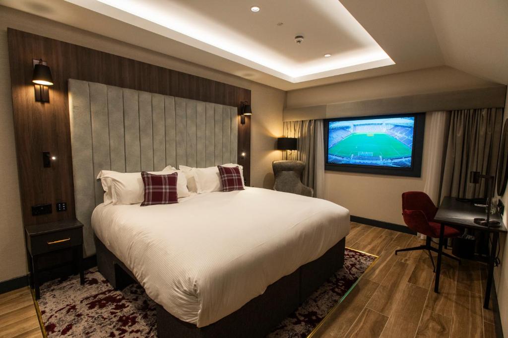 爱丁堡Tynecastle Park Hotel的一间卧室配有一张大床和电视