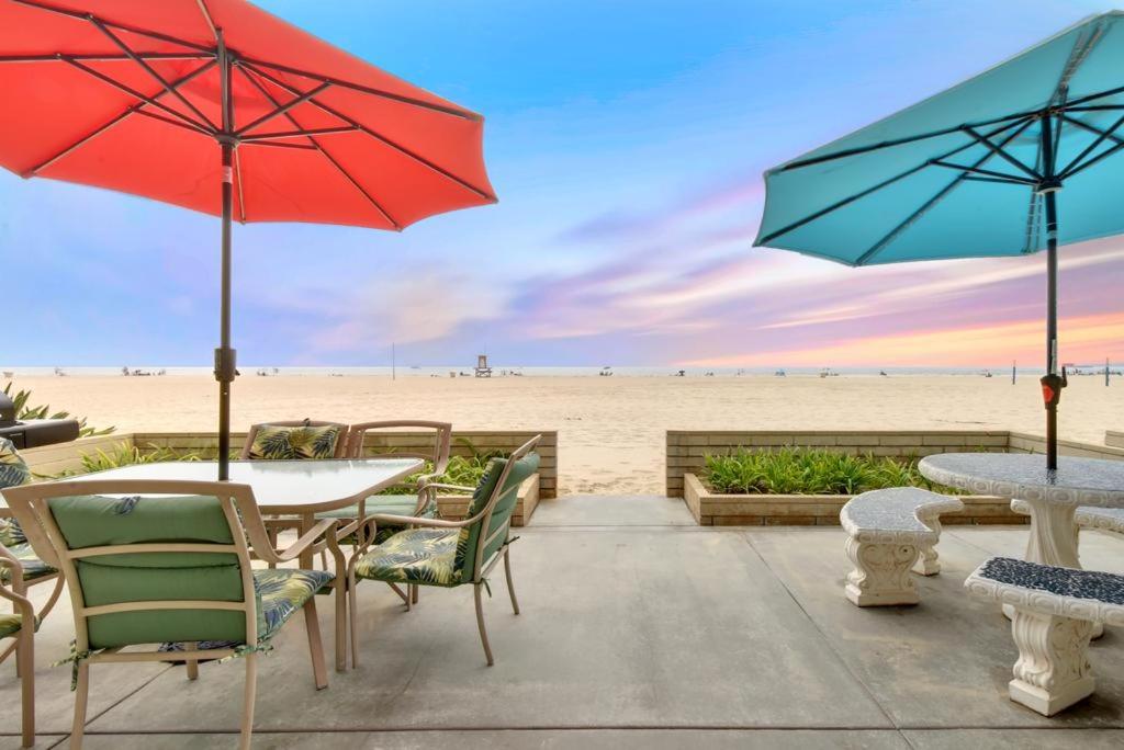 纽波特海滩West Newport Duplex on the Sand with Patio-Sleeps 12的海滩上带桌子和遮阳伞的庭院