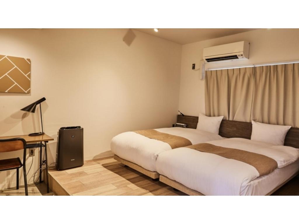 京都River Side Arashiyama - Vacation STAY 86031v的酒店客房设有两张床、一张桌子和一张书桌。