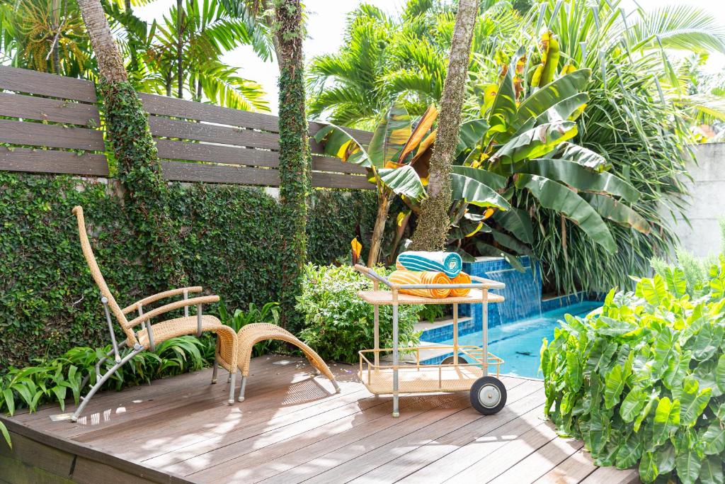 Four RoadsGarden Oasis 1 Villa With Private Pool的一个带椅子和桌子的木制甲板,毗邻一个游泳池
