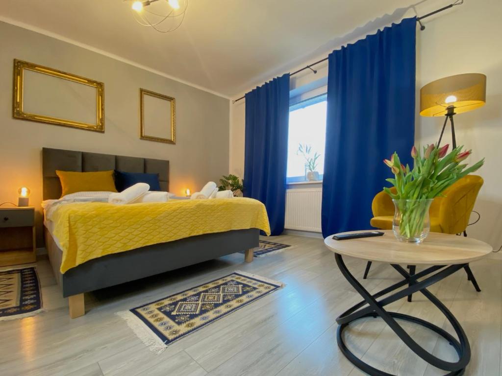 PodzamczeApartamenty Pod Zamkiem的一间卧室配有一张带蓝色窗帘的床和一张桌子