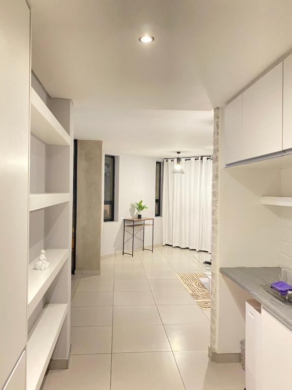 温特和克Windhoek Oliver perfect stays的厨房配有白色橱柜和瓷砖地板。