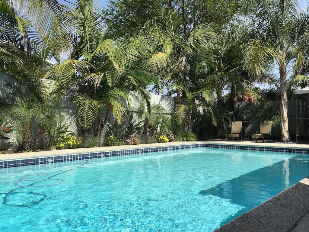 安纳海姆Palm Villa Disneyland Pool 4 Bedroom 3 Bath HotTub的一座种植了棕榈树的蓝色游泳池
