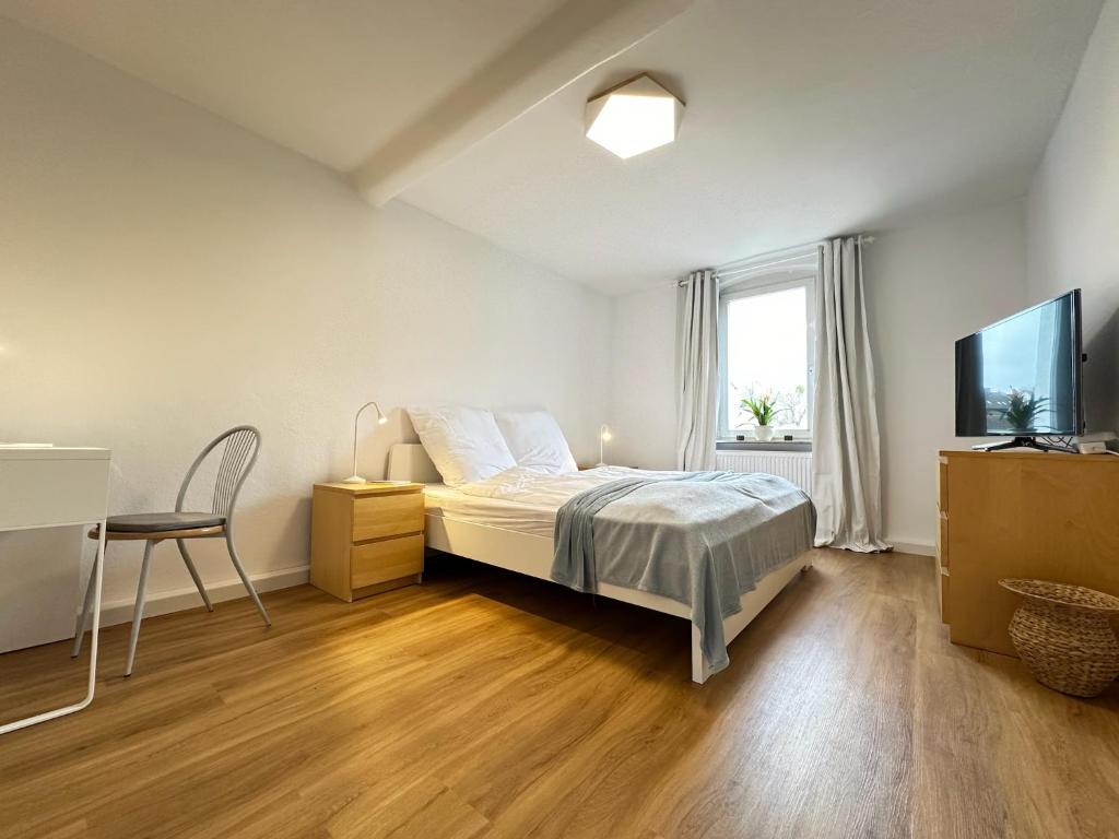 卡塞尔Cleo Apartments的一间卧室配有一张床、一张书桌和一台电视
