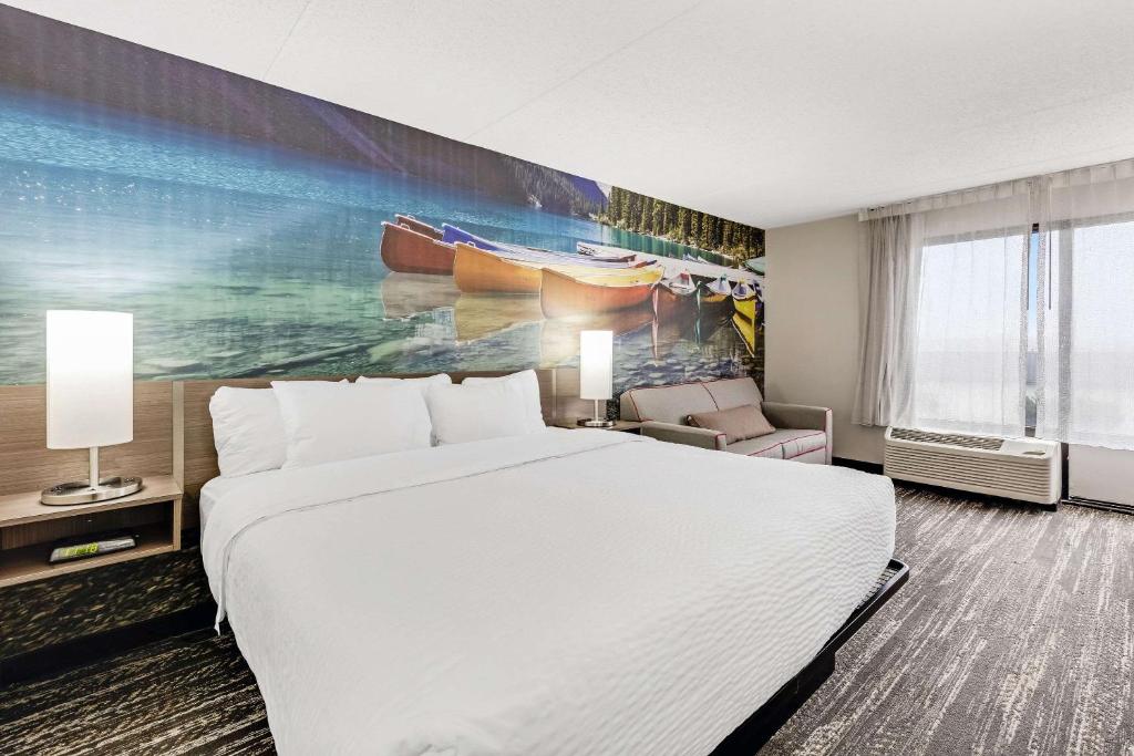 伊利Clarion Pointe by Choice Hotel的酒店客房设有一张床,墙上挂有绘画作品