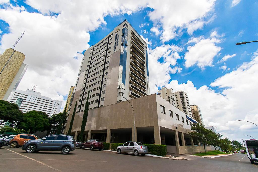 巴西利亚GS Properties - Nobile Monumental的停车场内有车辆停放的高楼