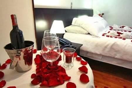 Mojón de LimaHOTEL MIRADOR LOS ANDES的一张桌子,上面放着两杯葡萄酒和红玫瑰