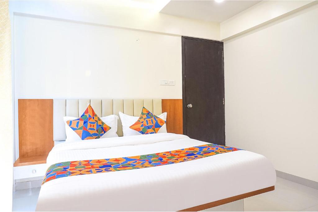 浦那FabHotel Majestic Luxurious的卧室配有一张带彩色枕头的大型白色床。