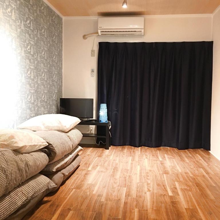 KasugabaruGuest House Fukuoka W305的客厅配有黑色窗帘和书桌