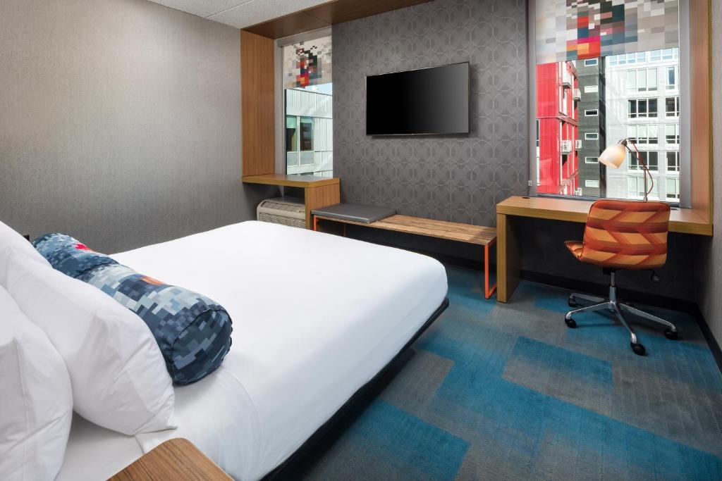 明尼阿波利斯Aloft Minneapolis的一间卧室配有一张床、一张书桌和一台电视。