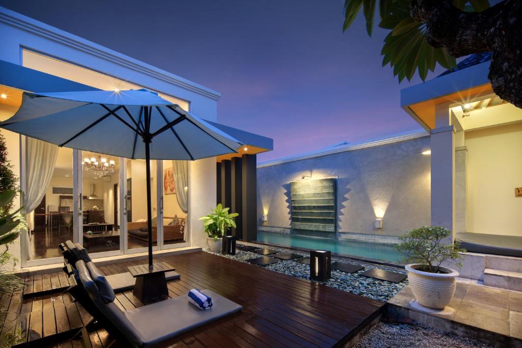 塞米亚克The Seiryu Boutique Bali Villas的一个带遮阳伞和游泳池的户外庭院