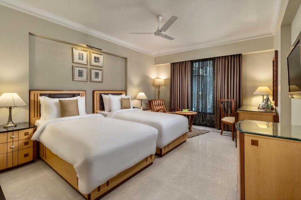 艾哈迈达巴德Sarovar Portico Kalupur Ahmedabad的酒店客房配有两张床和一张书桌