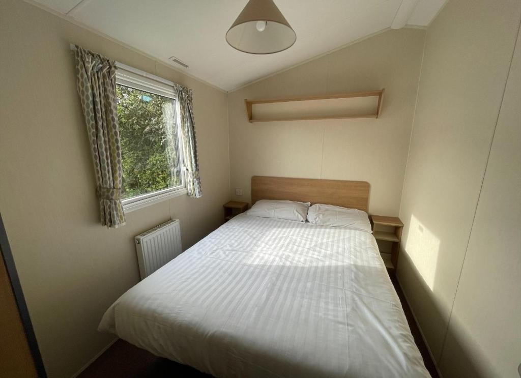 赫尔斯顿Sycamore Caravan的一间小卧室,配有白色的床和窗户
