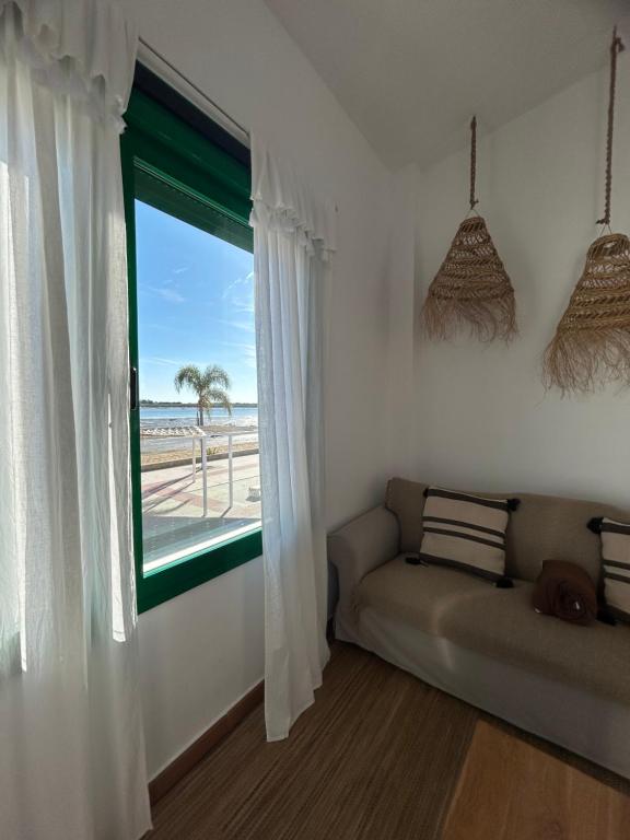 厄尔-汝姆披多Apartamento en primera línea de playa的客房设有沙发和享有海滩景致的窗户。