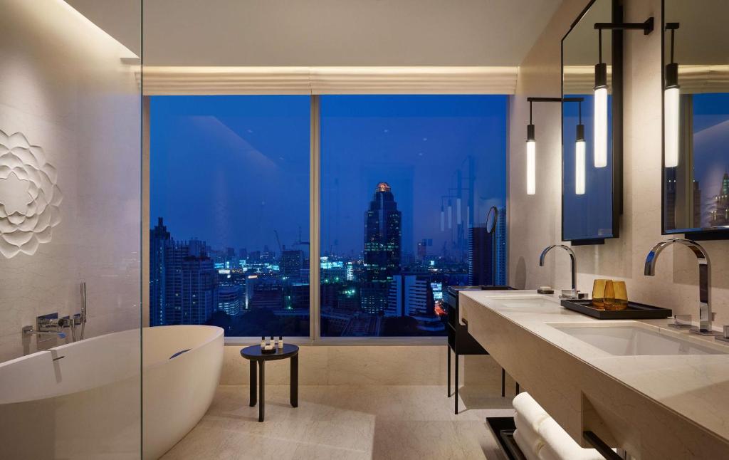 曼谷Park Hyatt Bangkok的带浴缸的浴室和市景窗户。