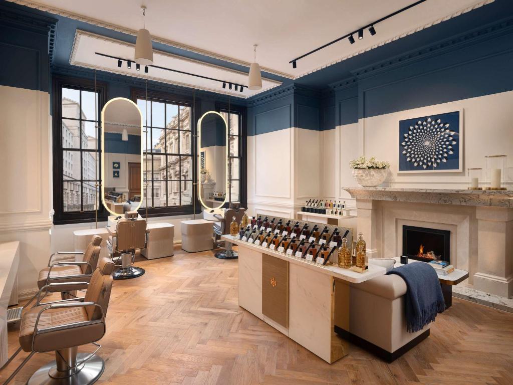 伦敦Raffles London at The OWO的客房设有带壁炉和椅子的沙龙。