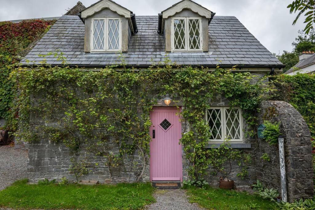 托玛斯镇The Rose Cottage的一座带粉红色门和两扇窗户的老房子