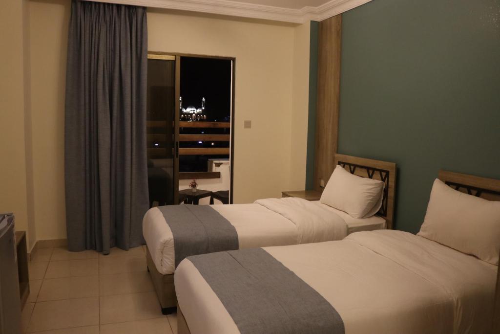 亚喀巴Mariam Boutique Hotel的酒店客房设有两张床和窗户。