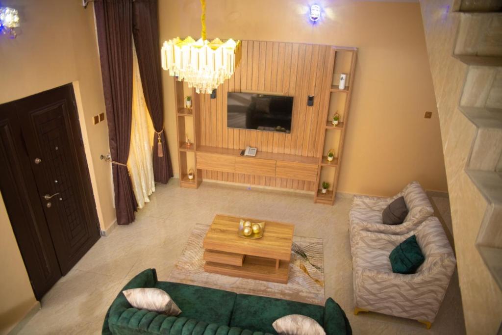 阿库雷Enny'scourt Service Apartment的客厅配有绿色沙发和桌子