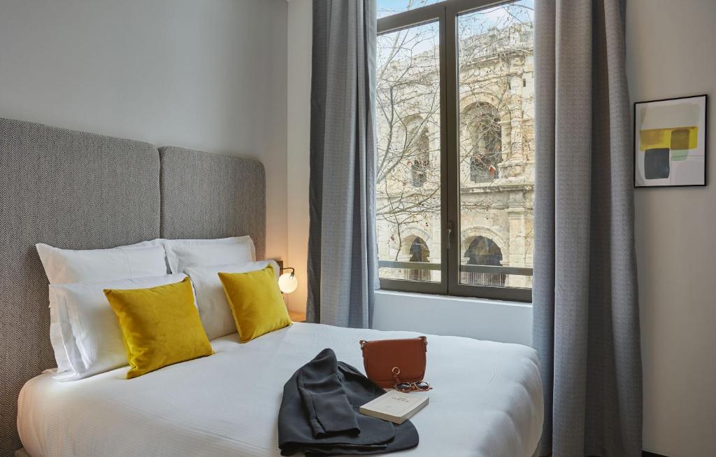 尼姆Odalys City Nîmes Arènes的酒店客房设有一张带笔记本电脑的床和窗户。