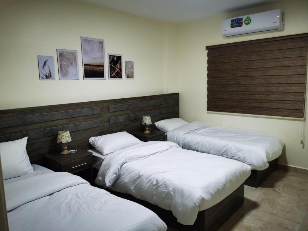 瓦迪穆萨Hospitality apartments的配有白色床单的客房内的三张床
