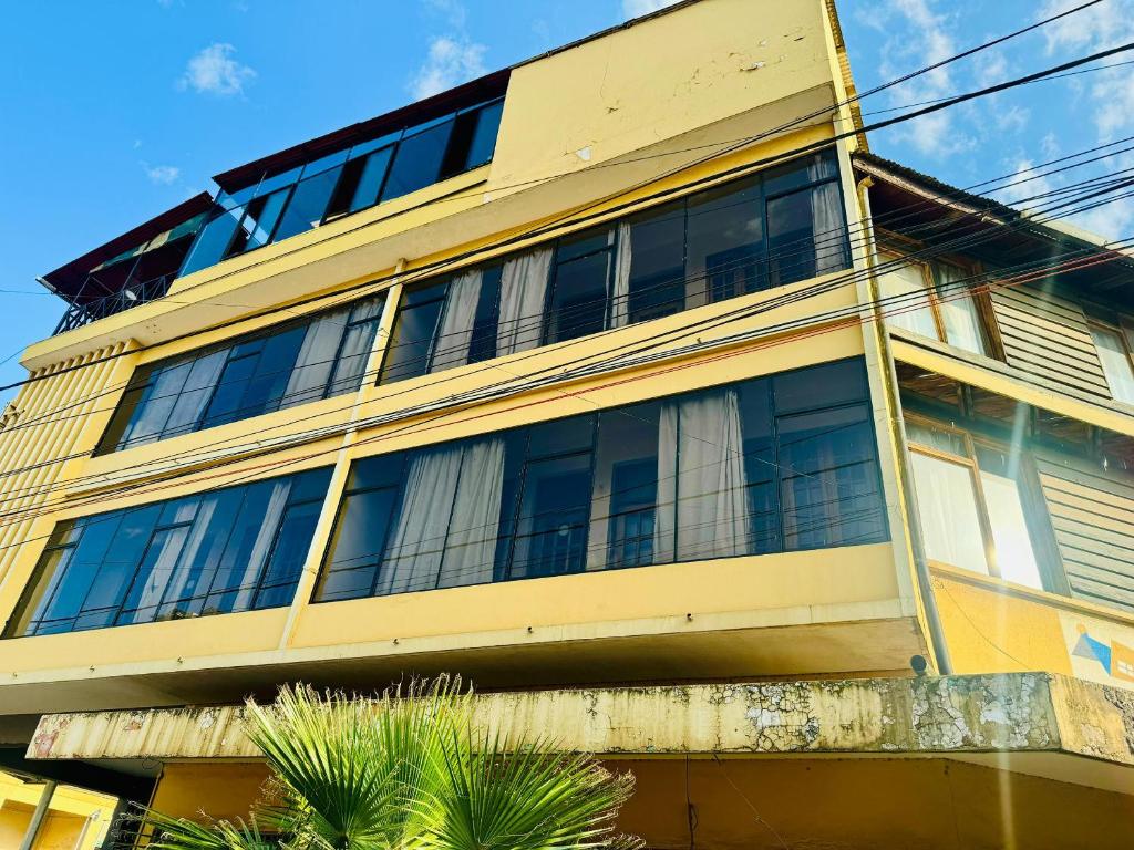 阿鲁沙Arusha Backpackers Hotel的一座黄色的建筑,有很多窗户