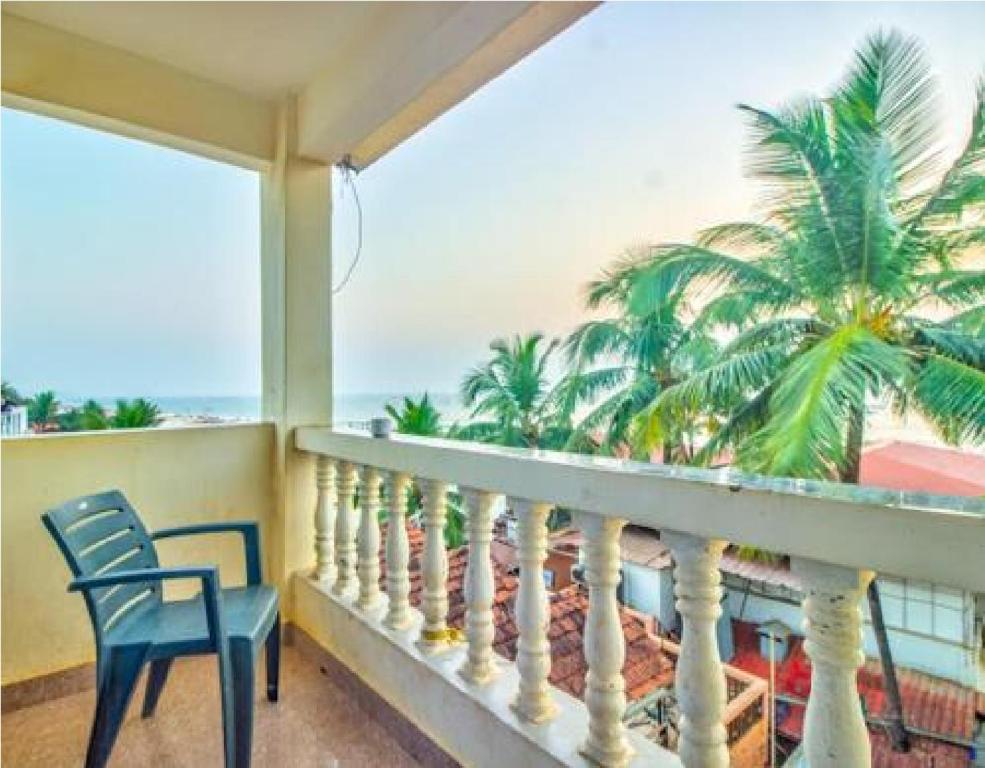 巴加Hotel Adam's Baga Beach Resort Goa - 2 minutes walk from Baga Beach的阳台配有椅子和棕榈树