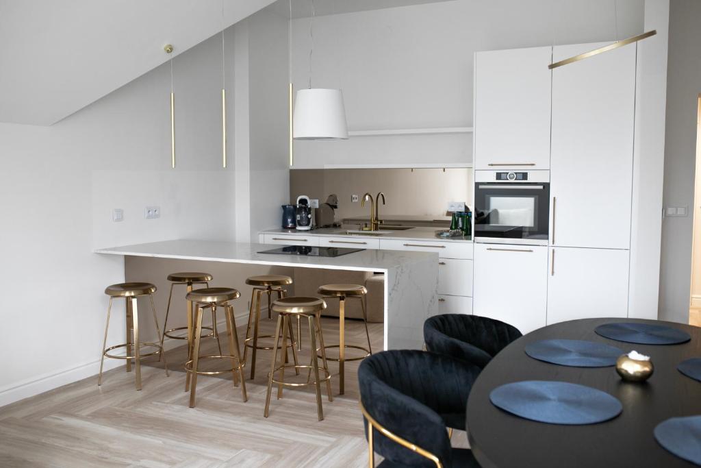 罗兹Srebrna Luxury Apartments - willa fabrykancka的厨房配有白色橱柜和酒吧凳子