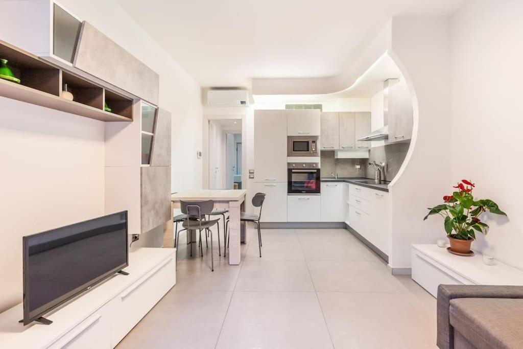 皮亚琴察Casa Maddalena的厨房以及带白色橱柜和平板电视的用餐室。