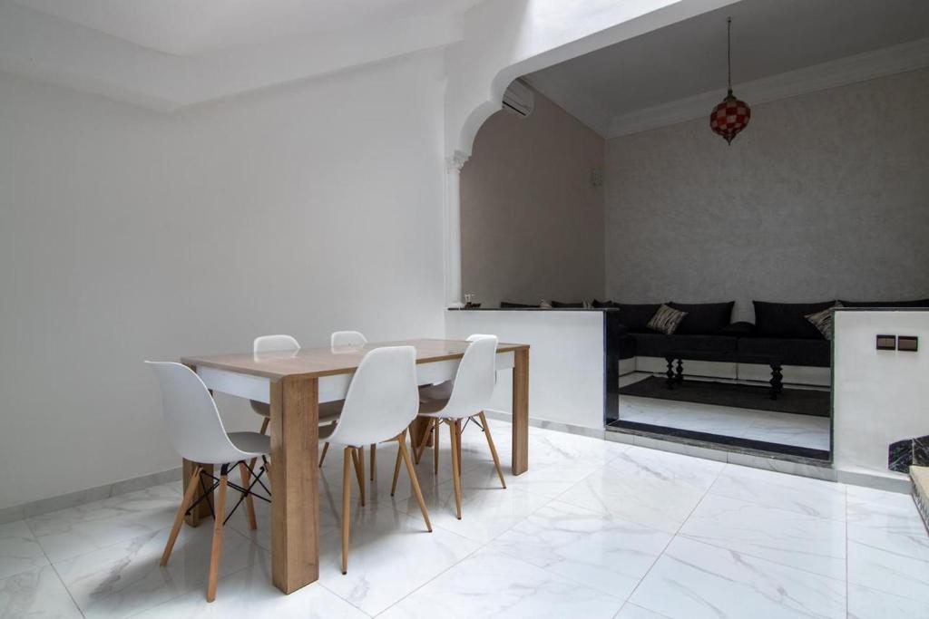 马拉喀什RIAD TAWSALANE的一间带桌子和白色椅子的用餐室