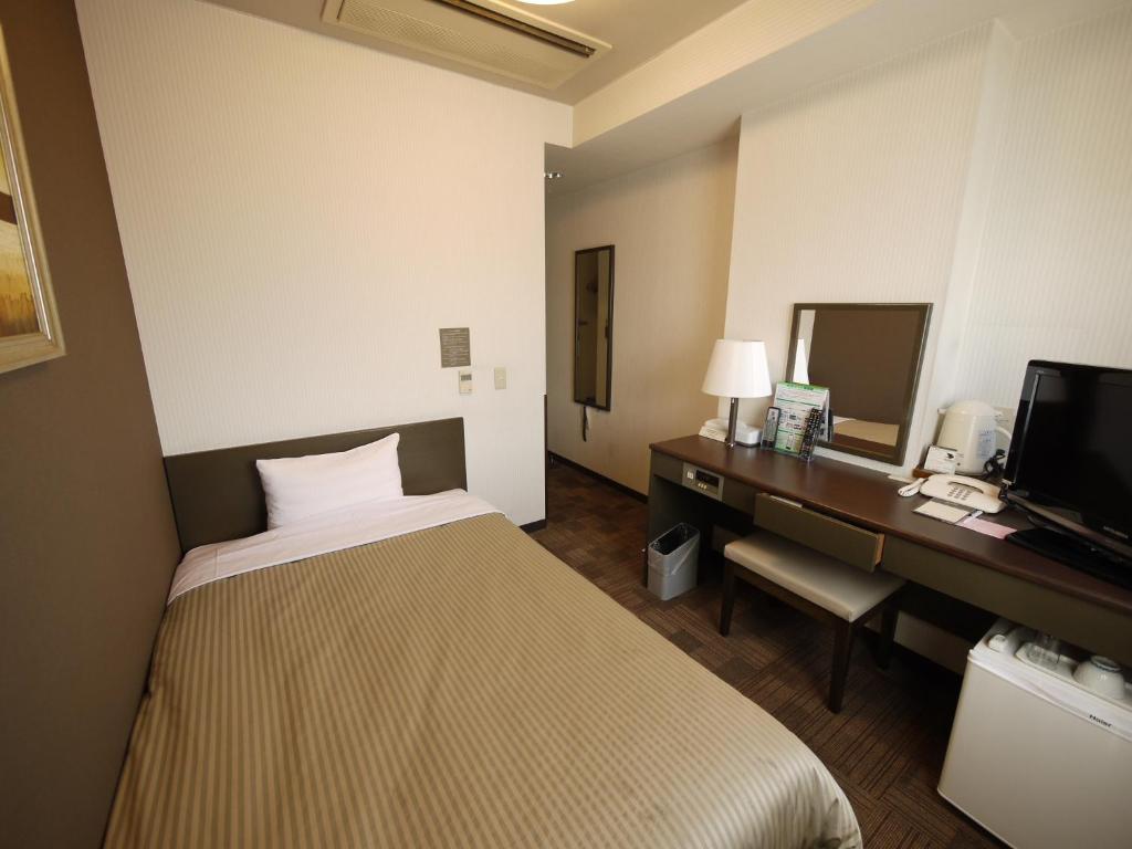 上野原市上野原阁路线酒店的酒店客房配有一张床、一张书桌和一台电视。