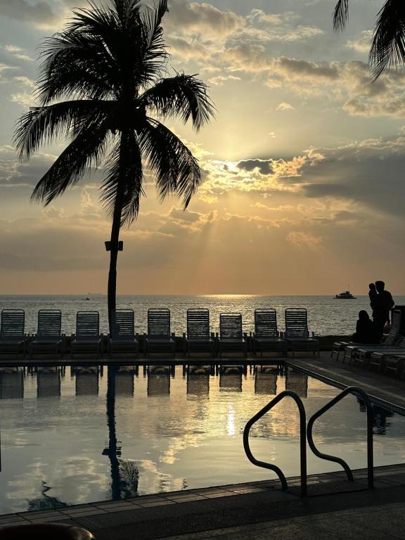 波德申Seafront38&39 - Regency Tg Tuan beach resort, port dickson的坐在游泳池旁棕榈树下的人