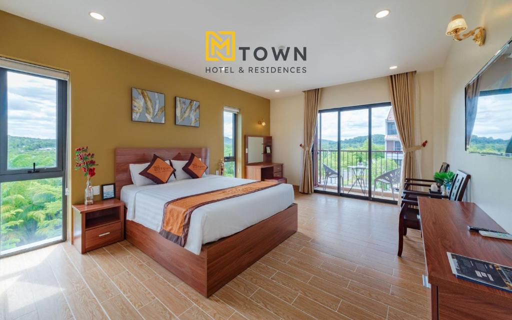 富国Luxy Park Hotel & Apartments - MTown的卧室配有一张床、一张书桌和窗户。