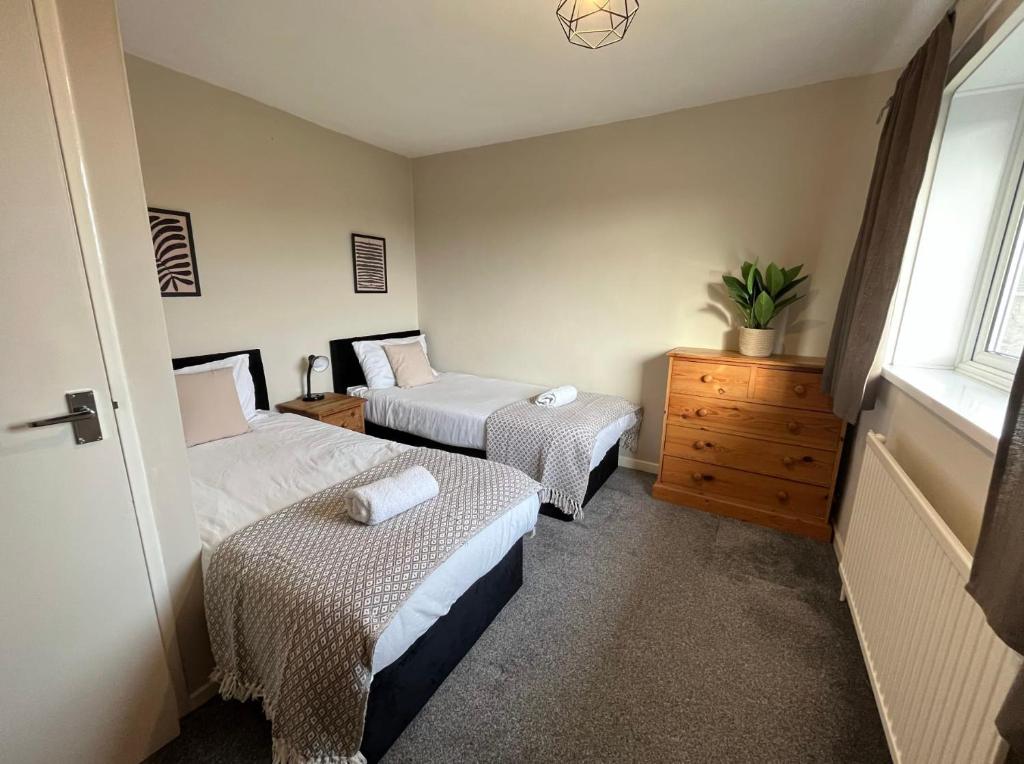 克劳利Contractors welcome 3 bed house with parking by Eagle Owl Stays的一间卧室设有两张床、一个梳妆台和窗户。