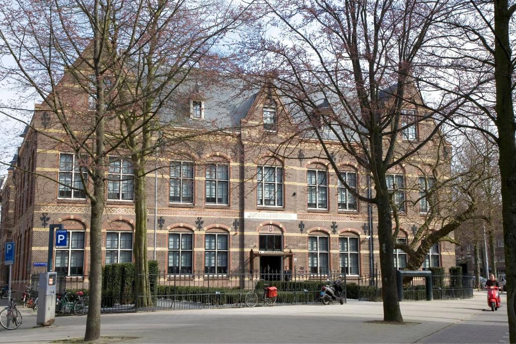 阿姆斯特丹The College Hotel Amsterdam, Autograph Collection的前面有树木的大型砖砌建筑