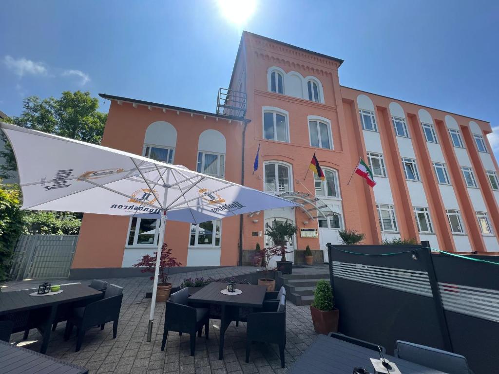 施韦尔姆穆莱泰奇酒店的大楼前的餐厅,配有桌子和遮阳伞