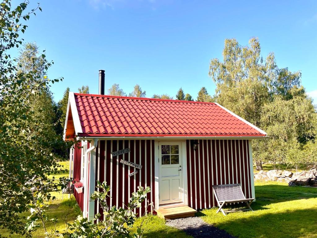 TingsrydPippis Cottage的草上带椅子的红白棚