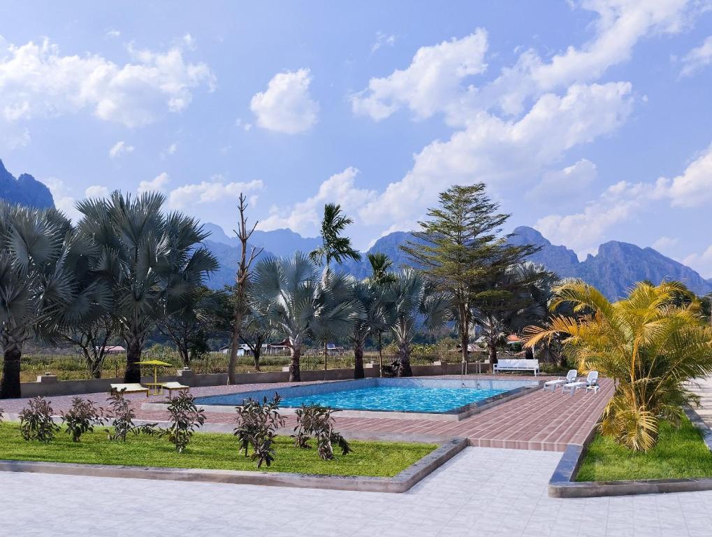 万荣Vang Vieng Romantic Place Resort的一座棕榈树和山脉环绕的游泳池