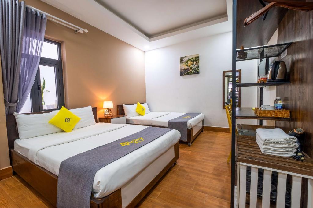 大叻Richy Dalat Hotel的酒店客房带两张床和一个架子