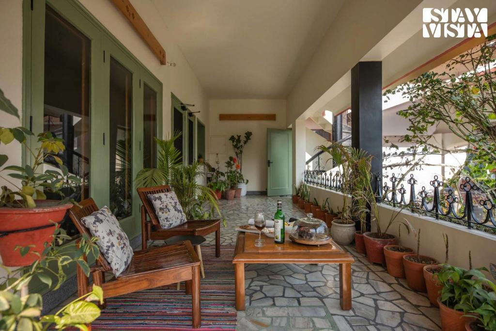 阿姆利则StayVista's Fiddle Leaf Home - Elegant Interiors, Spacious Lawn & Inviting Balcony的门廊,配有桌椅和盆栽植物