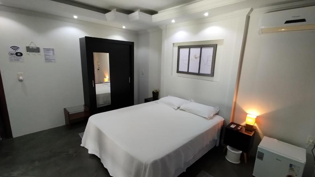 南圣克鲁斯Recanto do Sossego的卧室配有白色的床和镜子