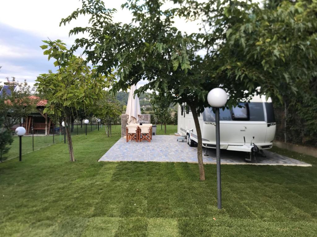 斯卡拉福卡斯Delightful RV Camper In a Peaceful Area near Sea.的停放在院子里的一辆长椅,配有桌椅